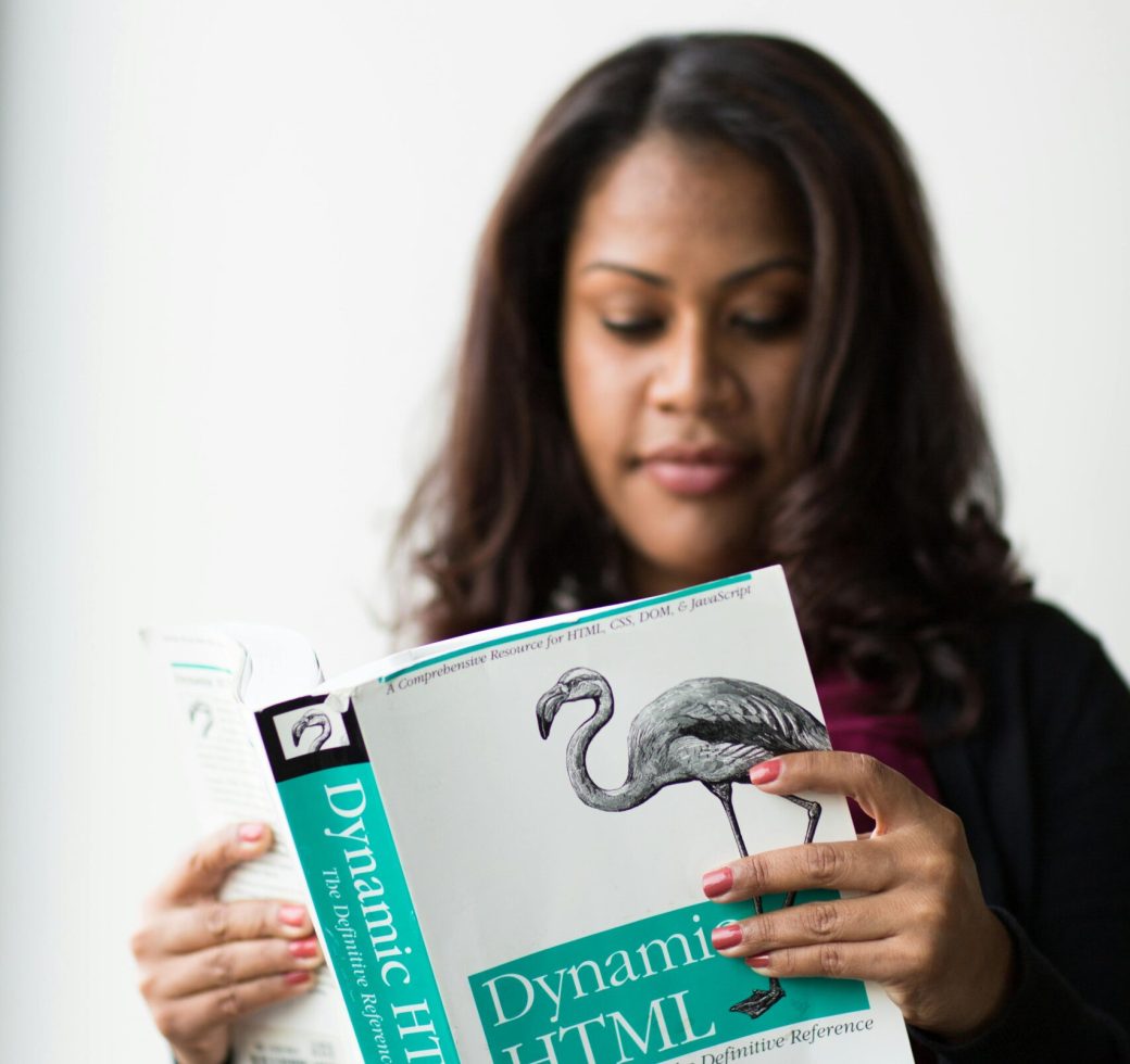 A woman focused on reading a book about Dynamic HTML indoors.