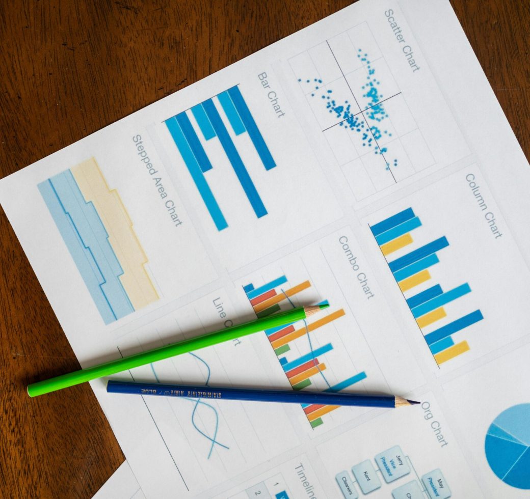 Top view of vibrant charts and colored pencils on wooden surface.
